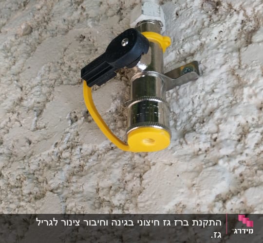 שסתום גז מתכת עם ידית שחורה על קיר